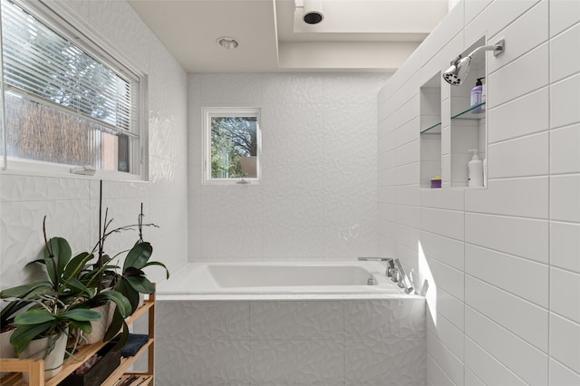 bathroom featuring tile walls and tiled tub