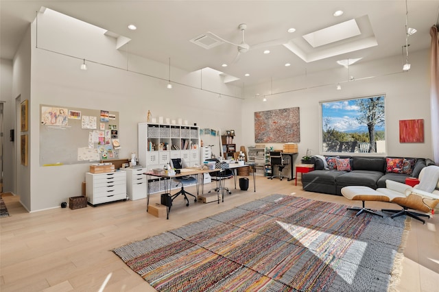 living room with a skylight, light hardwood / wood-style flooring, and a high ceiling