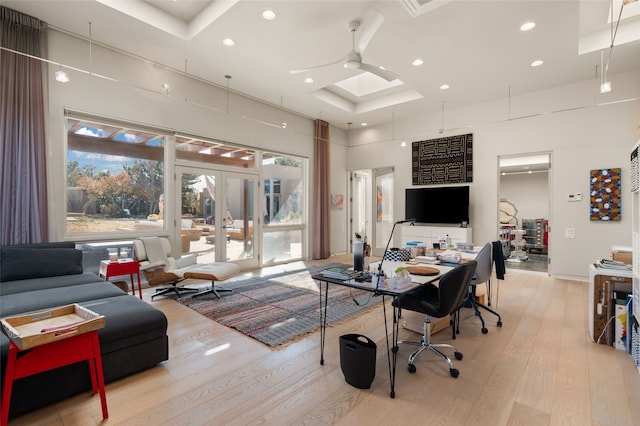 office area featuring a towering ceiling, ceiling fan, a raised ceiling, light wood-type flooring, and french doors