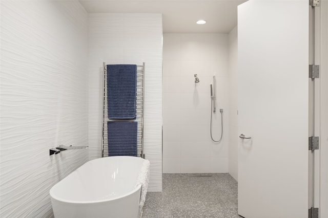 bathroom featuring separate shower and tub and tile walls