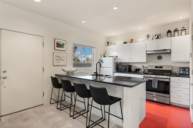 kitchen with a breakfast bar, white refrigerator, white cabinets, stainless steel range with gas cooktop, and kitchen peninsula