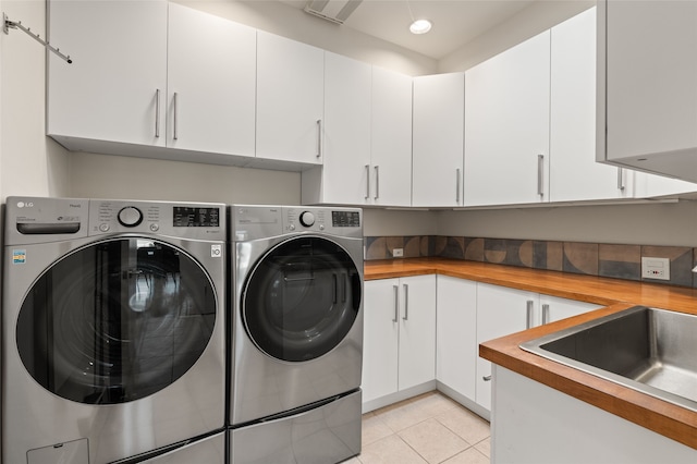 washroom with cabinets, washing machine and dryer, sink, and light tile patterned floors