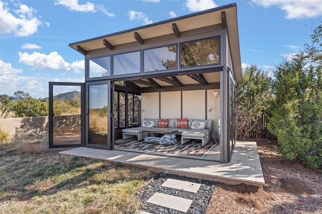 back of house with an outdoor living space and a patio