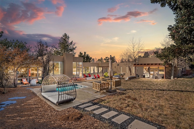 pool at dusk featuring a patio and a yard