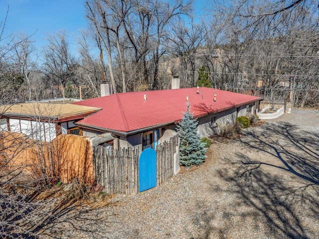 view of front of property featuring a chimney, fence, and metal roof