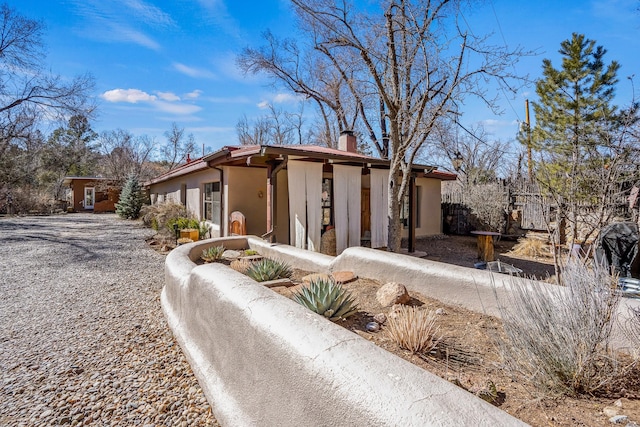 view of side of property featuring driveway, a chimney, and stucco siding