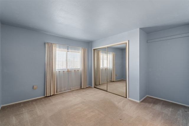 unfurnished bedroom featuring light colored carpet and a closet