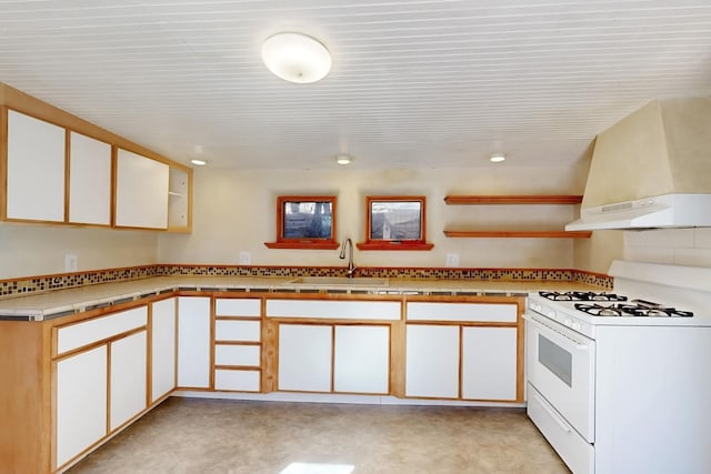 kitchen featuring kitchen peninsula, sink, white range with gas stovetop, and white cabinets