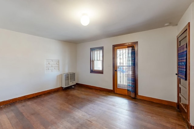 unfurnished room with dark hardwood / wood-style floors and heating unit