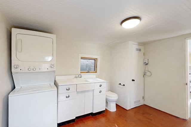 washroom featuring sink, hardwood / wood-style flooring, and stacked washing maching and dryer