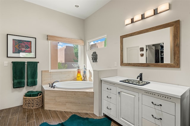 bathroom featuring a relaxing tiled tub and vanity