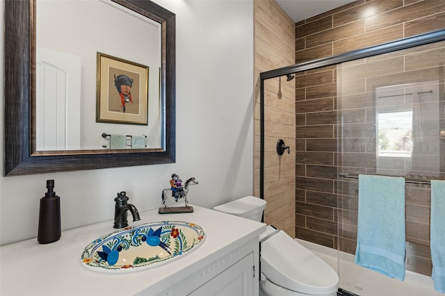 bathroom with vanity, a shower with door, and toilet