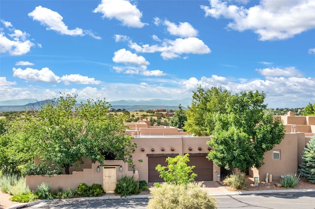 pueblo-style house with a garage and a mountain view