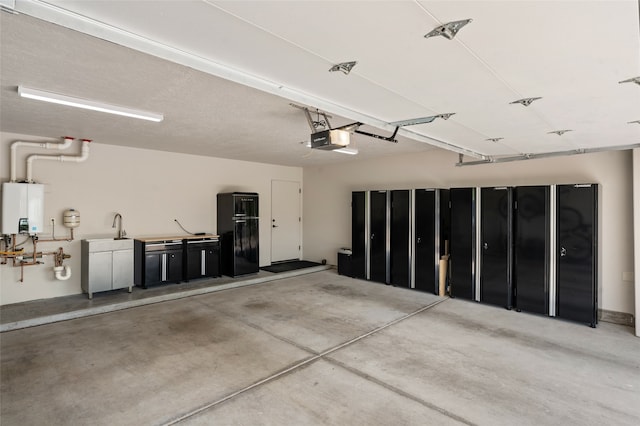 garage with tankless water heater, a garage door opener, black fridge, and sink