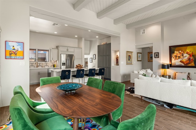 dining area featuring wood-type flooring and beamed ceiling