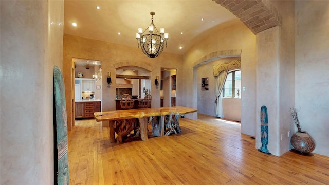 dining space with lofted ceiling, a chandelier, and light wood-type flooring