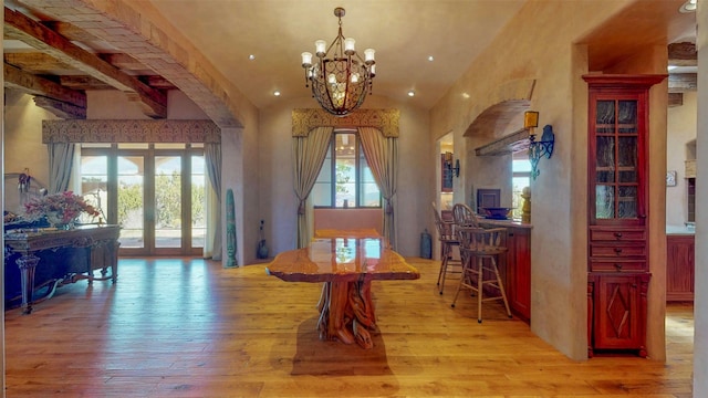 dining area with light hardwood / wood-style flooring, a chandelier, and vaulted ceiling