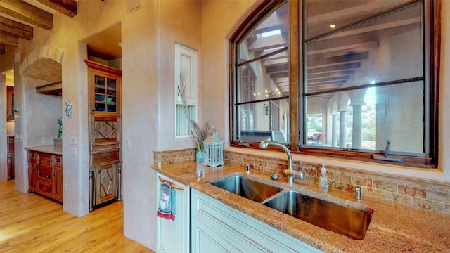 kitchen featuring light stone counters, light hardwood / wood-style floors, dishwasher, and sink