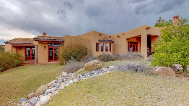 pueblo-style house with a front lawn and french doors