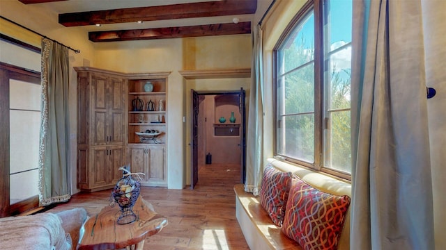 interior space featuring a healthy amount of sunlight, beam ceiling, and light hardwood / wood-style floors