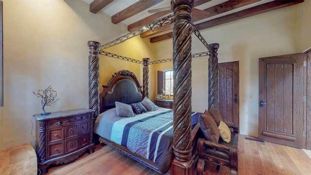 bedroom with beam ceiling and light wood-type flooring