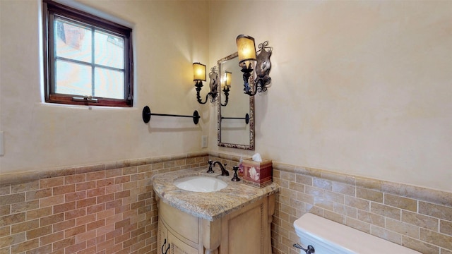 bathroom with tile walls, vanity, and toilet