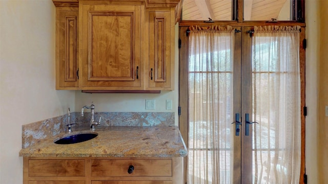 kitchen featuring light stone countertops, sink, and french doors