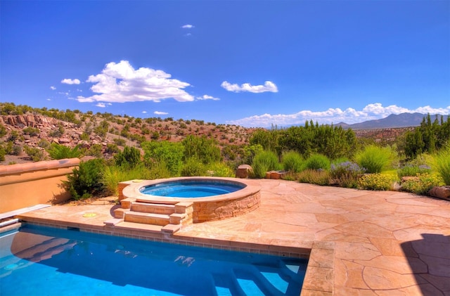 view of pool with an in ground hot tub, a mountain view, and a patio area