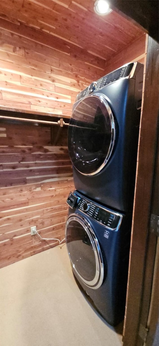 clothes washing area with wood ceiling, wooden walls, and stacked washer / dryer