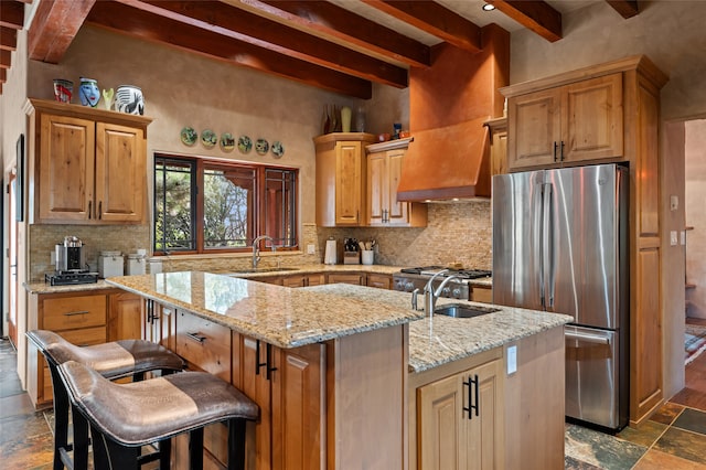 kitchen featuring stainless steel refrigerator, sink, an island with sink, and decorative backsplash