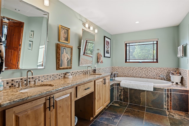 bathroom featuring a relaxing tiled tub, vanity, and tasteful backsplash