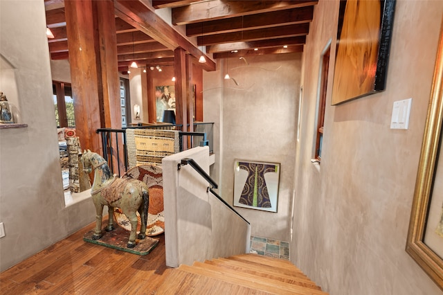 stairs featuring hardwood / wood-style flooring and beamed ceiling