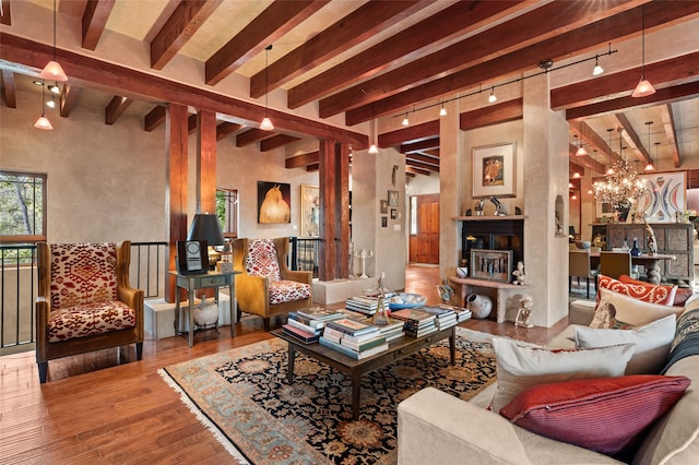 living room with beamed ceiling, wood-type flooring, rail lighting, and a chandelier