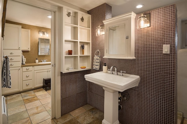 bathroom featuring tile walls, backsplash, and double sink