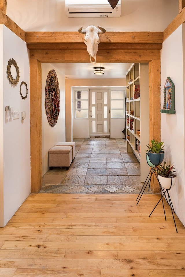 doorway to outside featuring hardwood / wood-style floors, a wall mounted AC, and beam ceiling