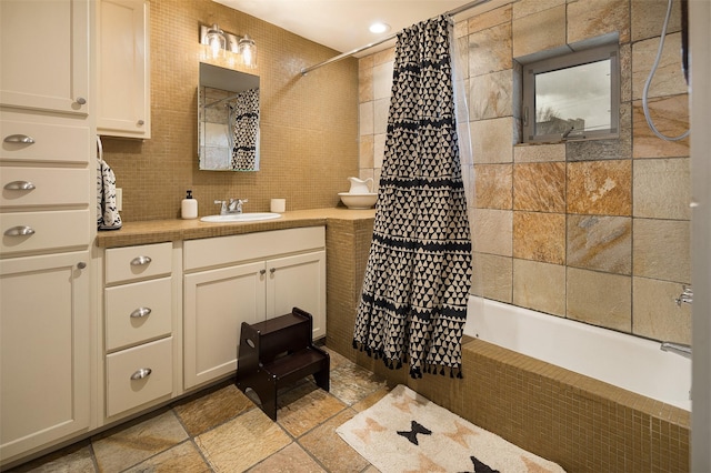 bathroom with shower / bath combination with curtain, vanity, tasteful backsplash, and tile walls