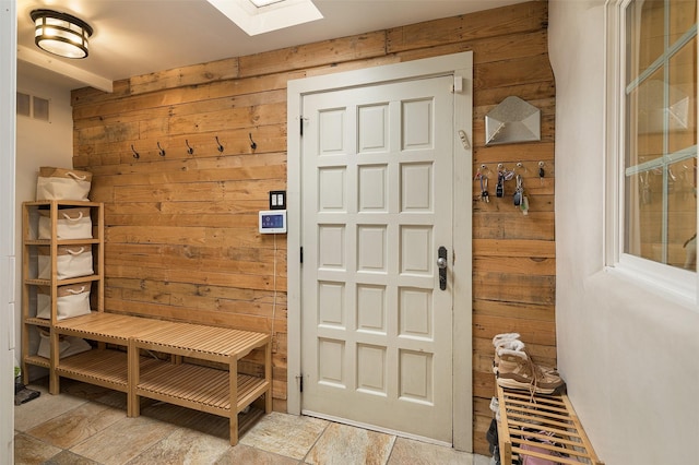 mudroom featuring a skylight and wooden walls