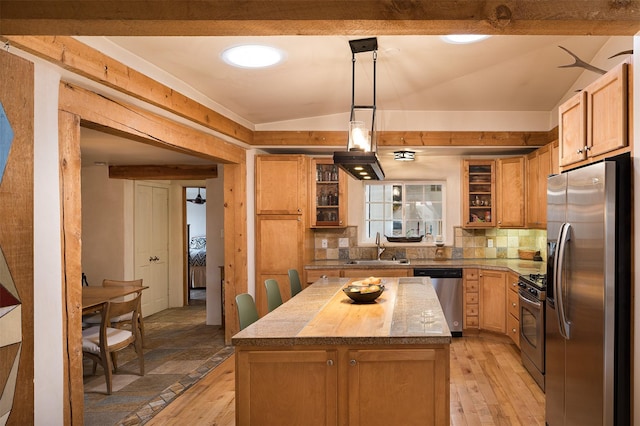 kitchen with lofted ceiling, sink, decorative light fixtures, a center island, and stainless steel appliances