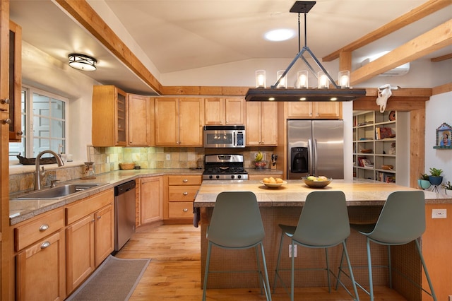 kitchen featuring vaulted ceiling, a kitchen island, pendant lighting, sink, and stainless steel appliances