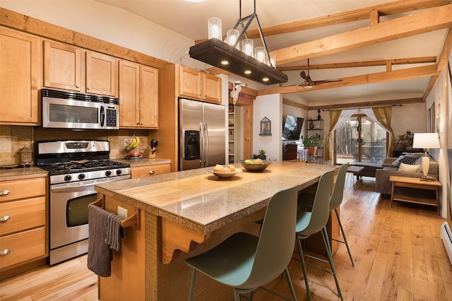 kitchen featuring a kitchen island, backsplash, a breakfast bar area, and appliances with stainless steel finishes