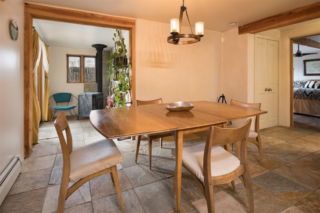 dining room with a wood stove, a chandelier, and baseboard heating