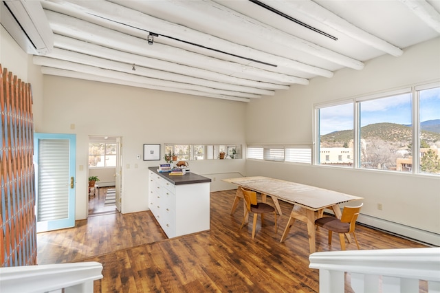 dining space with a mountain view, dark hardwood / wood-style floors, and beamed ceiling