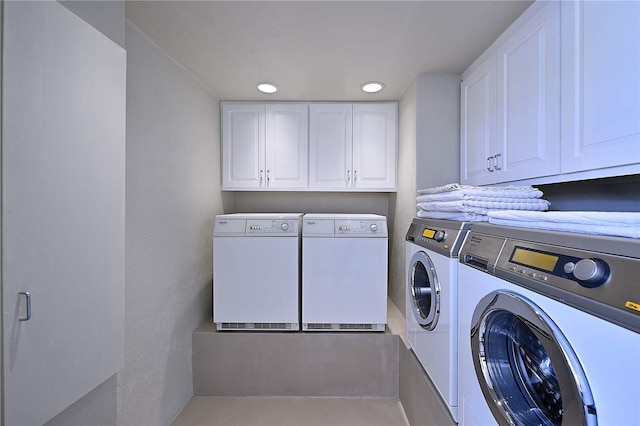 laundry area with separate washer and dryer and cabinets