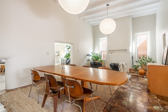 dining space featuring beamed ceiling and a towering ceiling