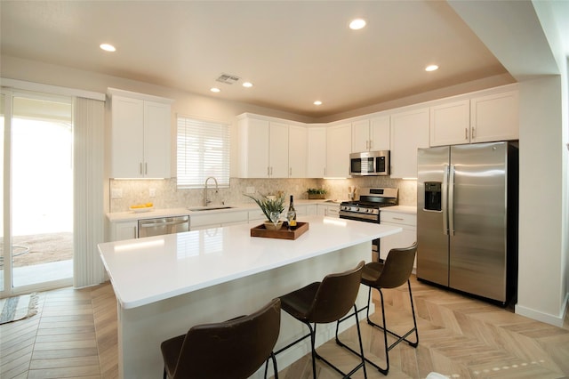 kitchen featuring white cabinetry, sink, stainless steel appliances, and light parquet flooring