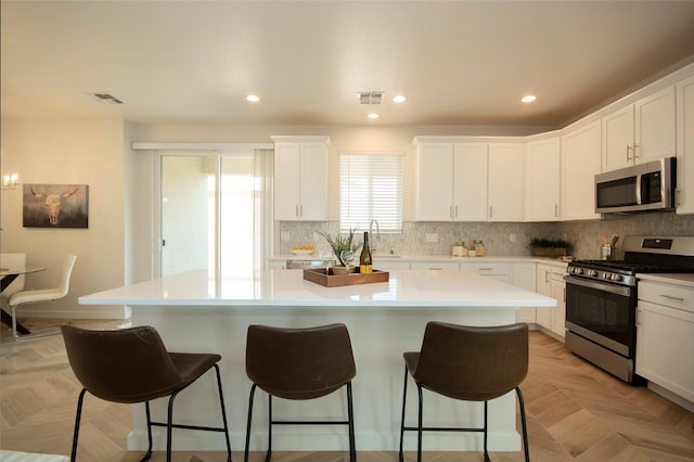 kitchen featuring stainless steel appliances, a center island, and light parquet flooring