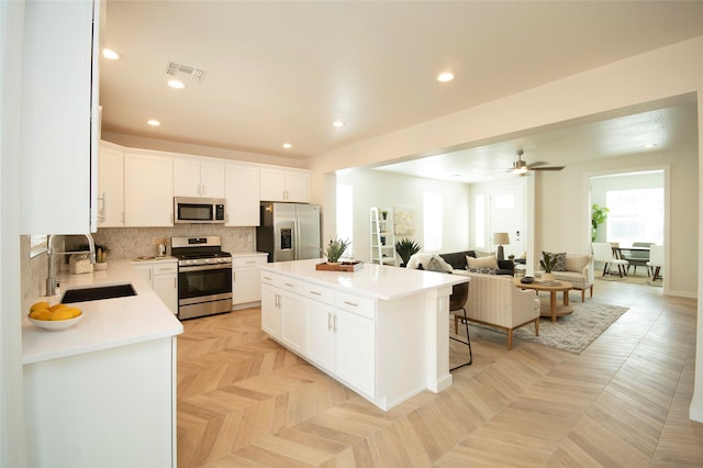 kitchen featuring sink, stainless steel appliances, white cabinets, and a kitchen island