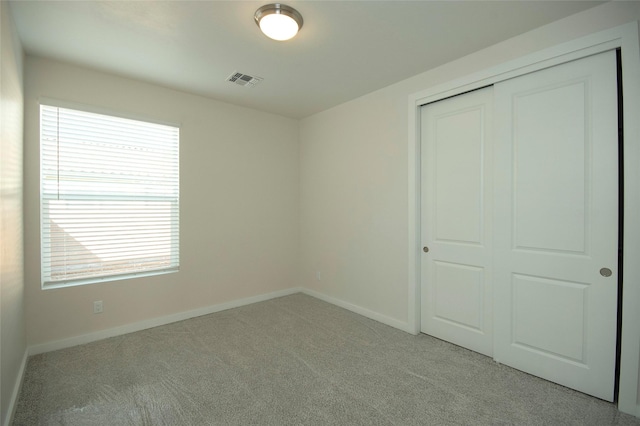 unfurnished bedroom with light colored carpet and a closet