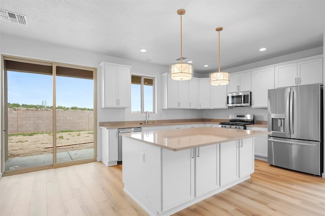 87 Cadena Loop, Los Alamos, NM 87547 - kitchen with stainless steel appliances, light wood-type flooring, a kitchen island, white cabinets, and light countertops