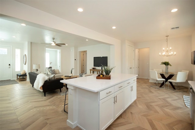 kitchen with light parquet floors, a kitchen breakfast bar, white cabinets, a kitchen island, and decorative light fixtures